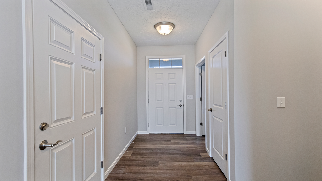 an empty hallway with white doors and a door to a closet