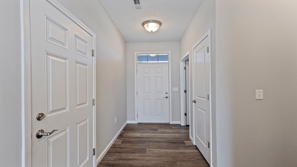 an empty hallway with white doors and a door to a closet