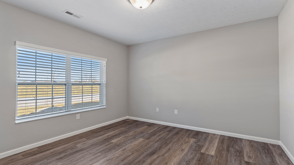 an empty living room with a large window and wooden floors