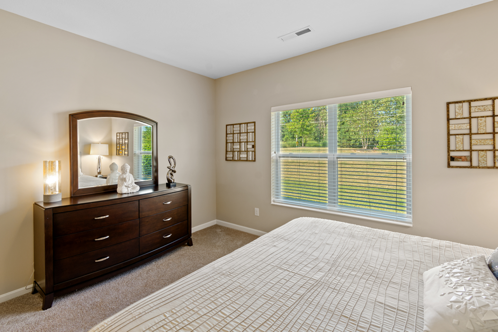 a bedroom with a bed and a dresser and a window