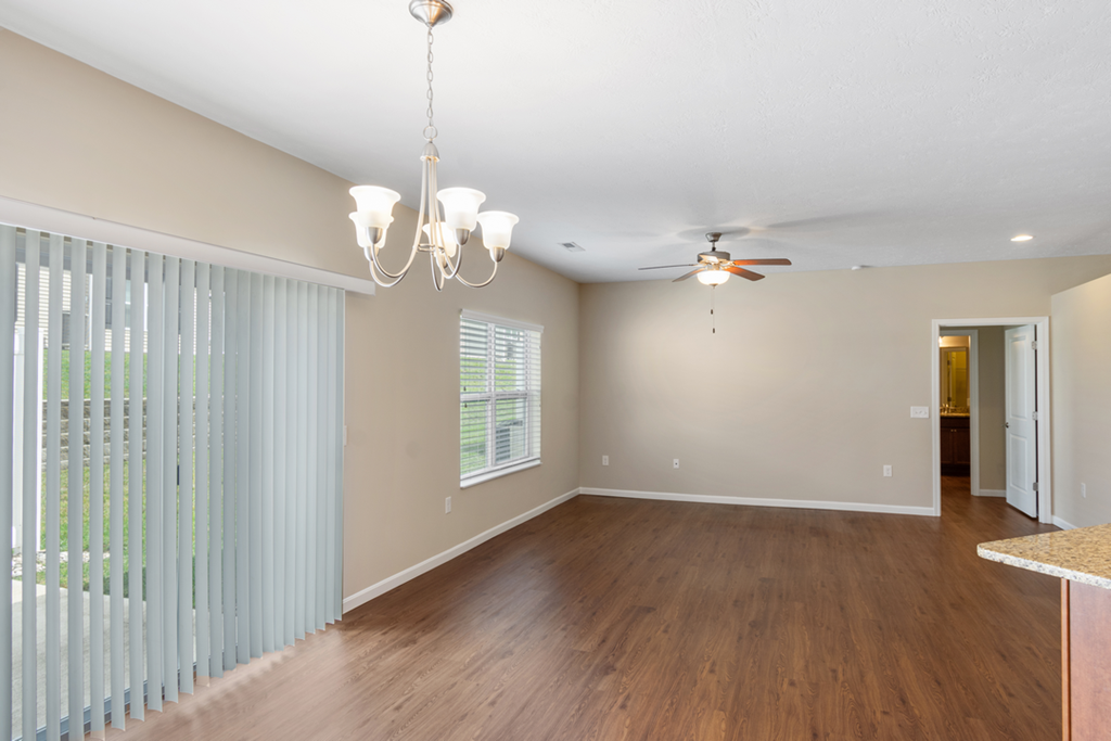 an empty living room with a ceiling fan and a window