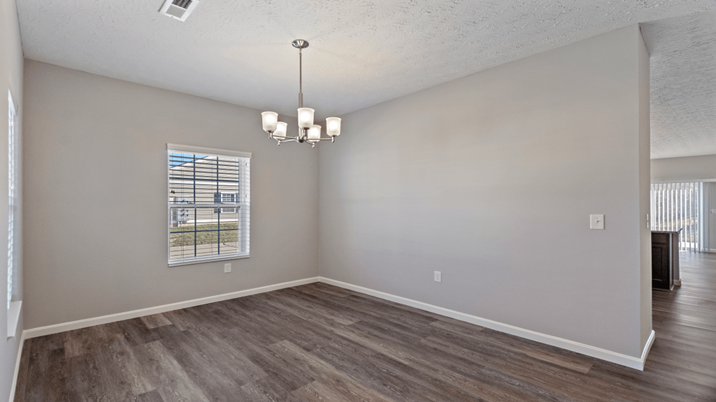 an empty living room with wood flooring and a window