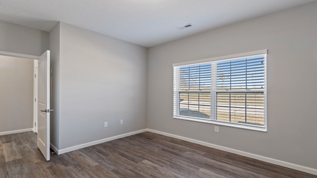 an empty living room with a large window and wooden floors