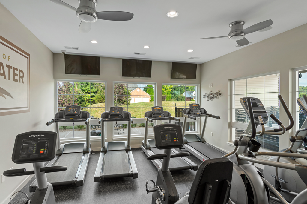 A gym with treadmills and a wall sign that says