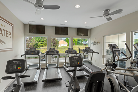 A gym with treadmills and a wall sign that says