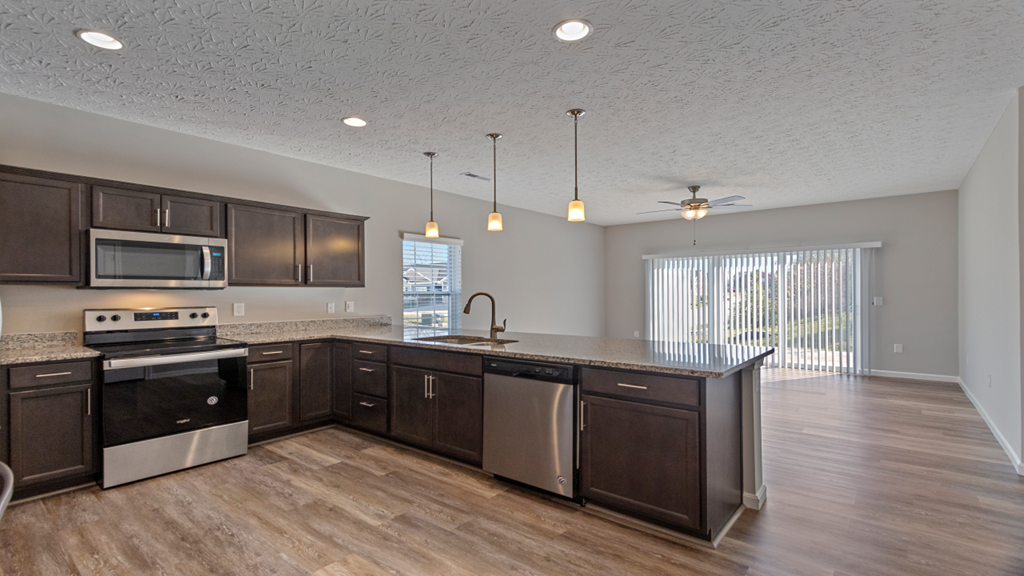 an open kitchen and living room with wood flooring and stainless steel appliances