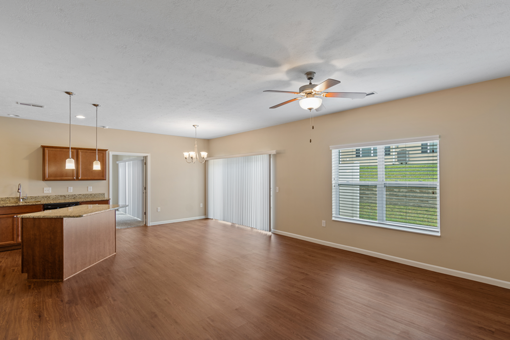 an empty living room and kitchen with a ceiling fan