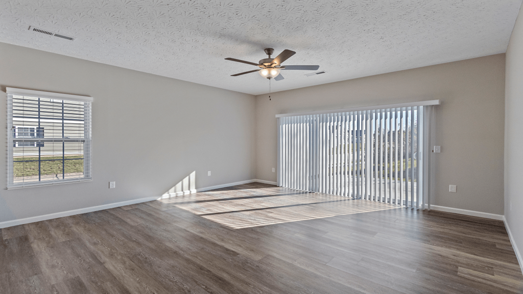 an empty living room with a ceiling fan and a window