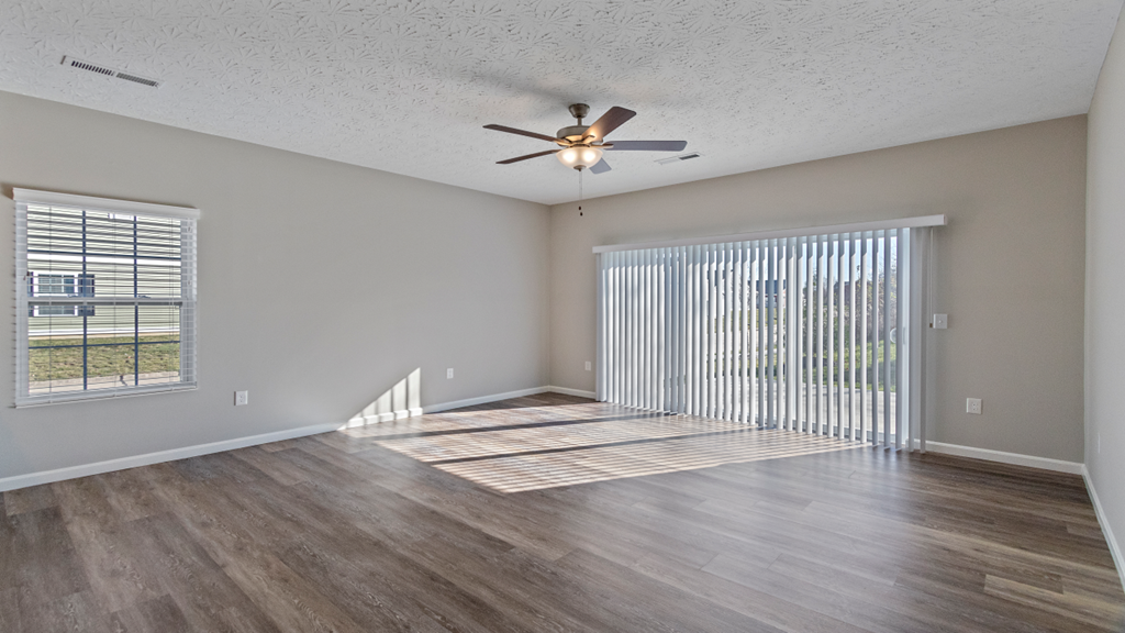 an empty living room with a ceiling fan and a window
