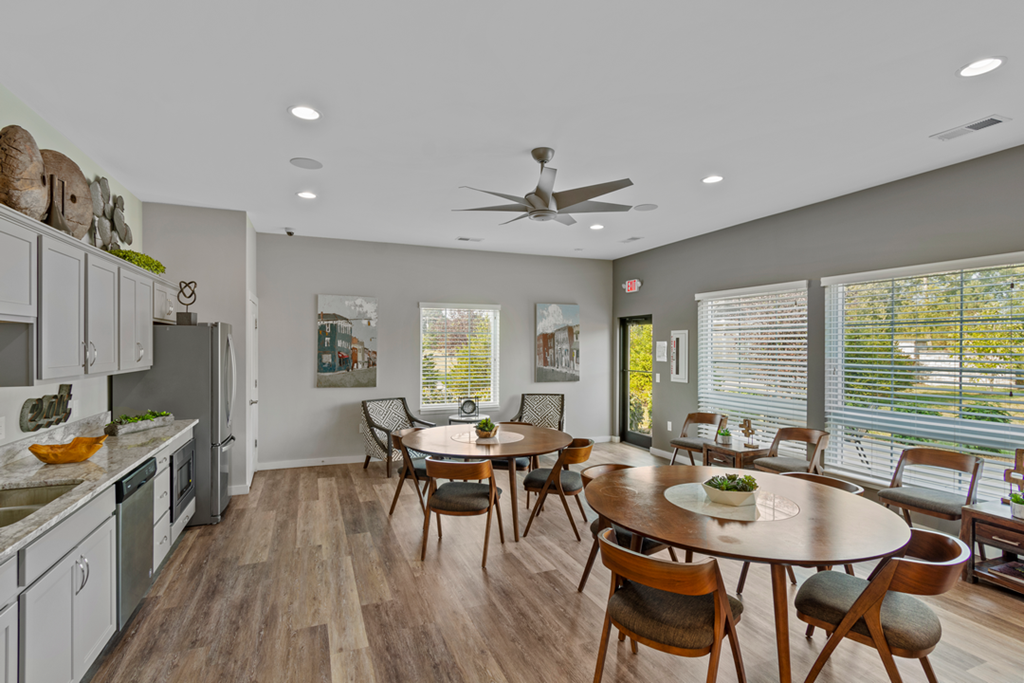 a dining room with a table and chairs and a kitchen with a ceiling fan