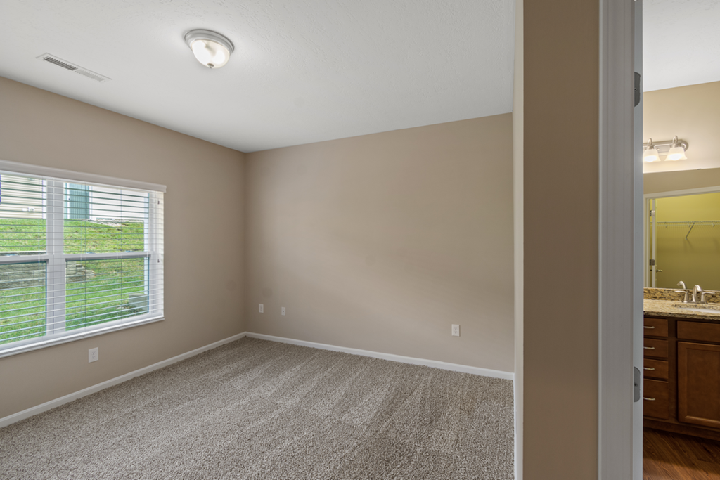 an empty bedroom with a large window and a bathroom