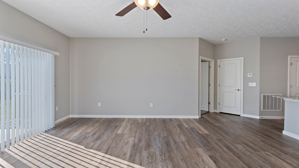 an empty living room with a ceiling fan