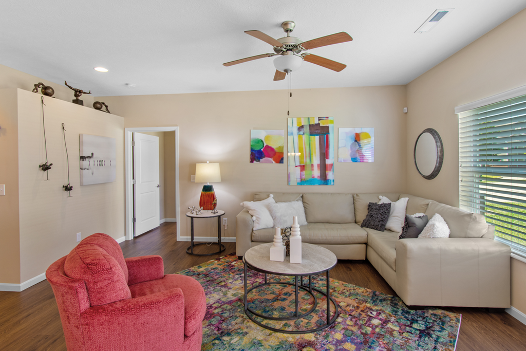 a living room with a couch and a chair and a ceiling fan