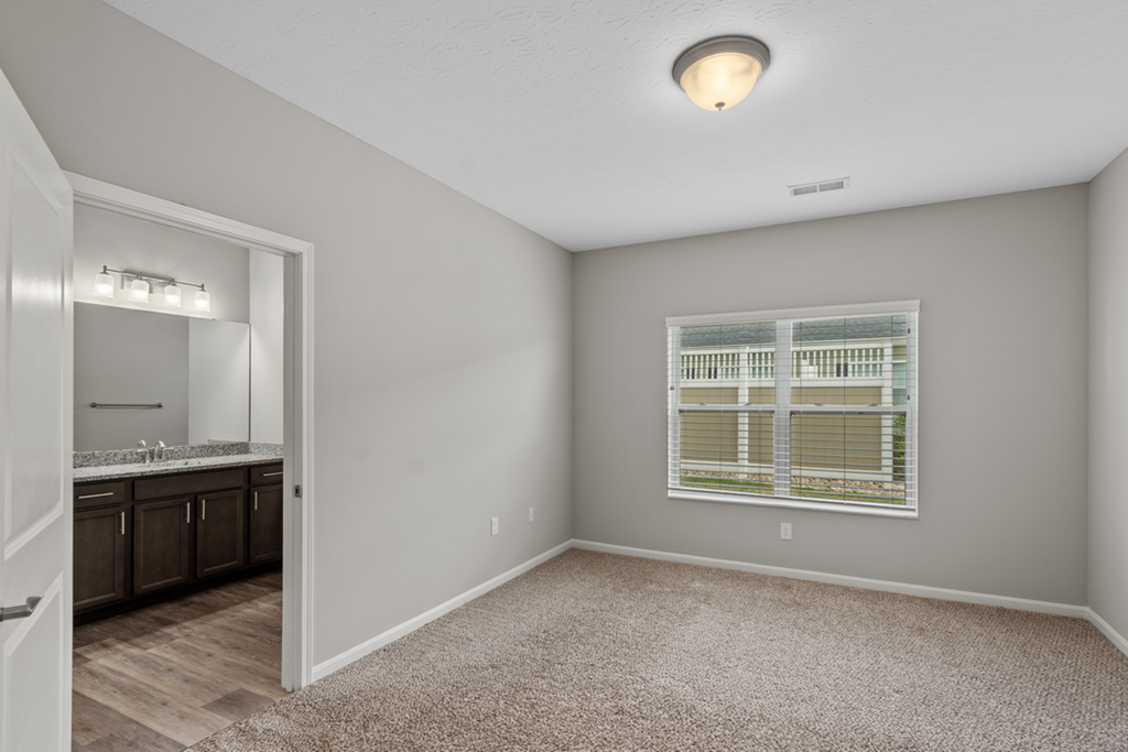 an empty bedroom with a large window and a bathroom