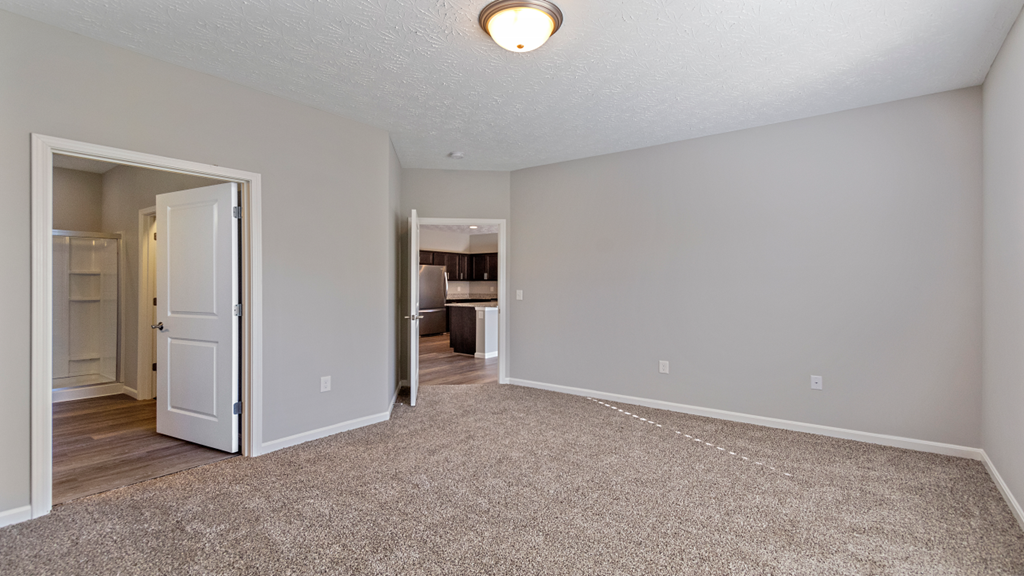 an empty living room with a door open to a bedroom