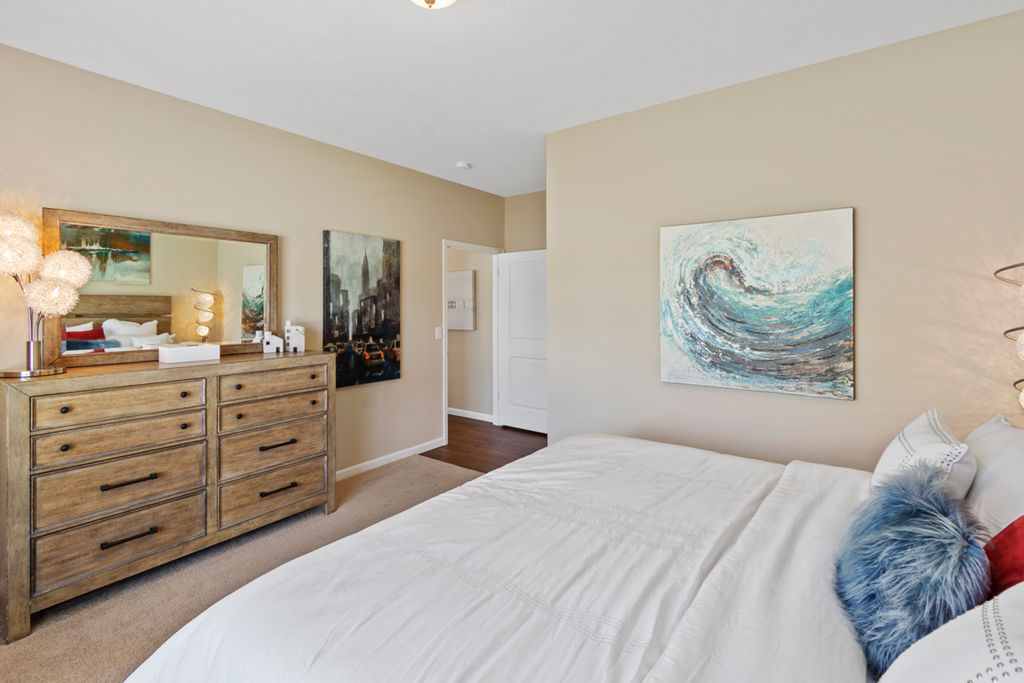 a bedroom with a bed and a dresser and a painting on the wall
