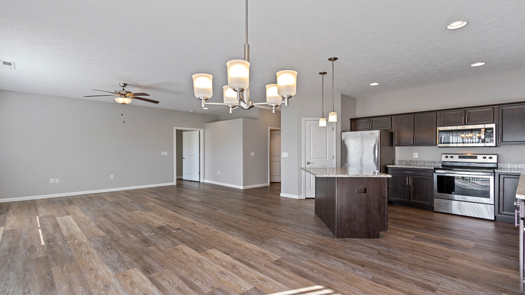 an open kitchen and living room with wood flooring and stainless steel appliances