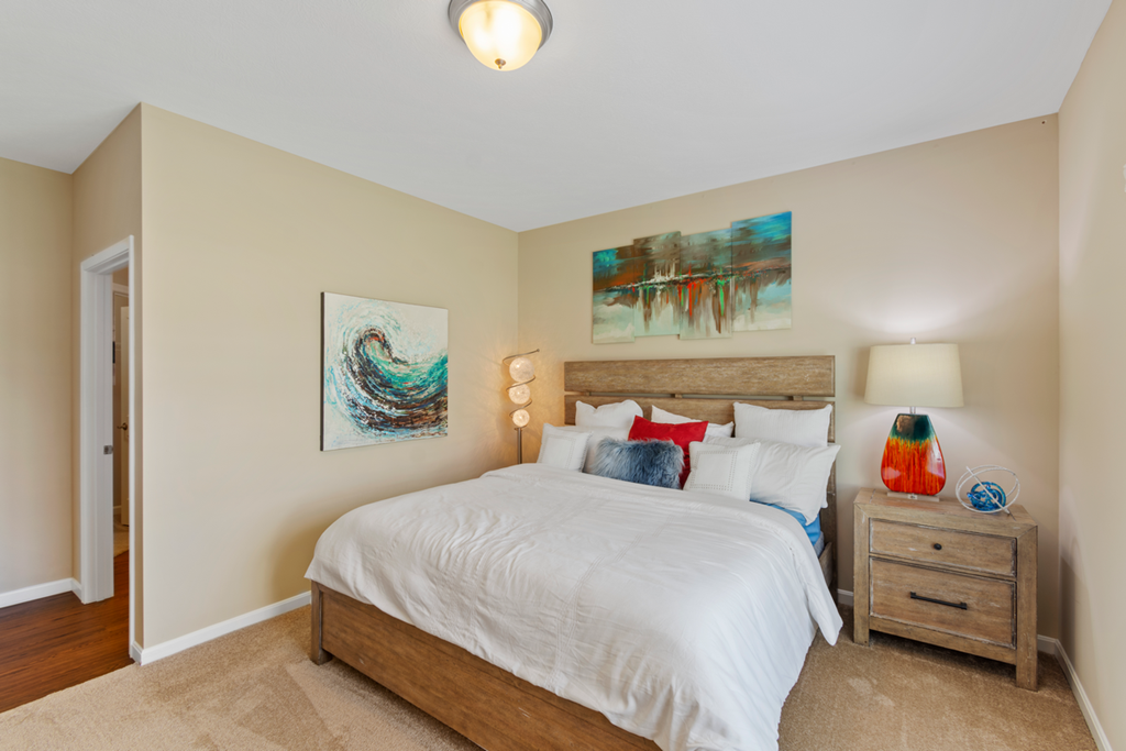 a bedroom with beige walls and a bed with white sheets and pillows