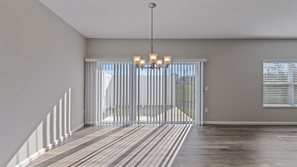 an empty living room with sliding glass doors and a chandelier