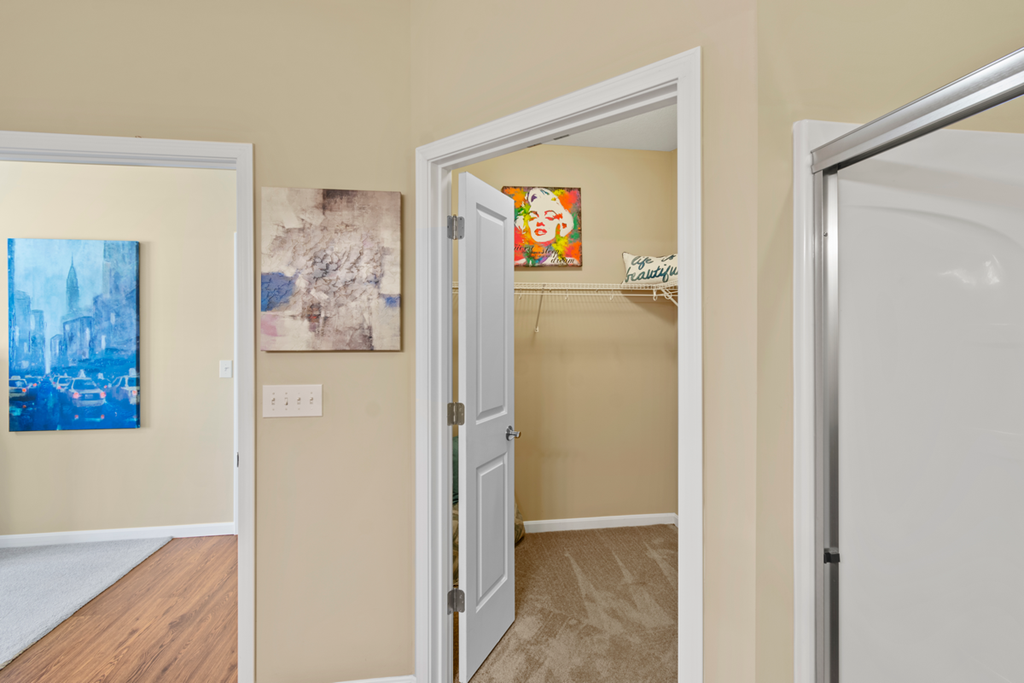a hallway with an open door to a closet and a door into a room with