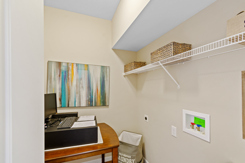 a home office with a desk and a laptop computer and a shelf with a closet