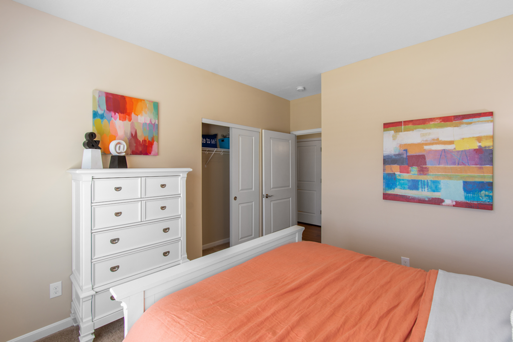 a bedroom with a white dresser and a bed