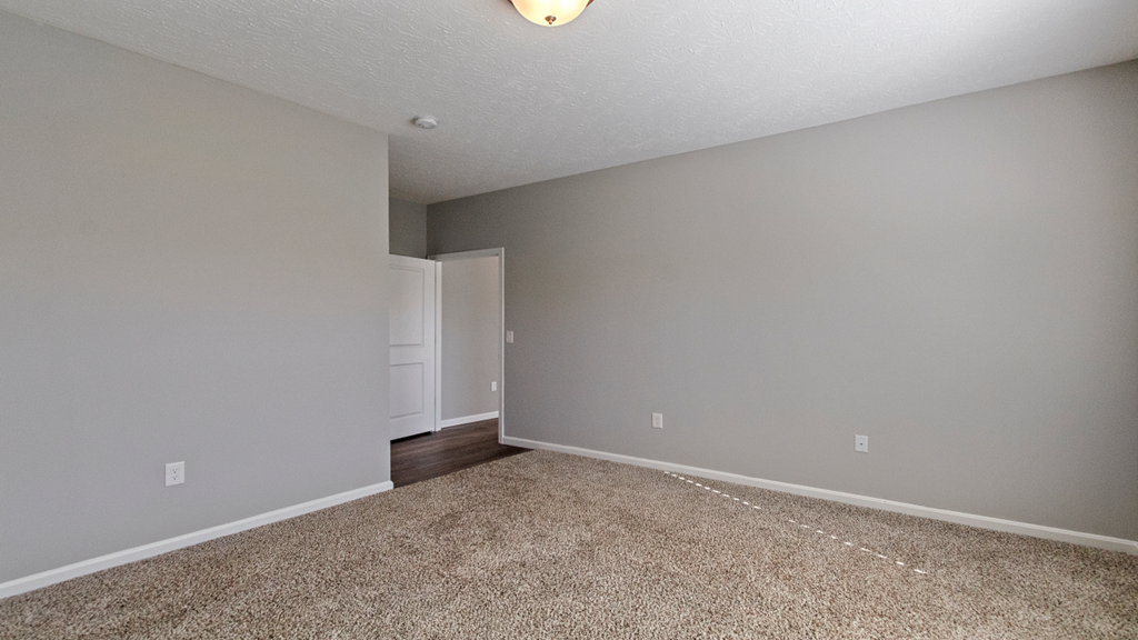 an empty living room with carpet and grey walls