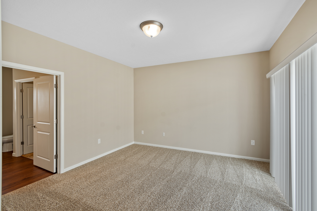 an empty bedroom with a door to a closet and a carpeted floor
