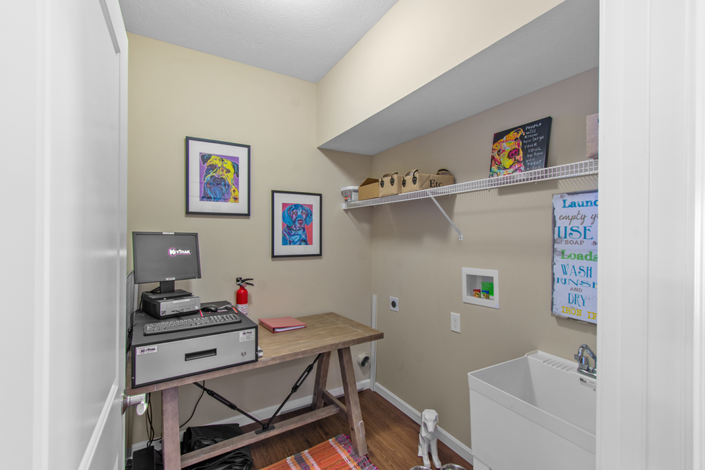 a home office with a computer desk and a sink