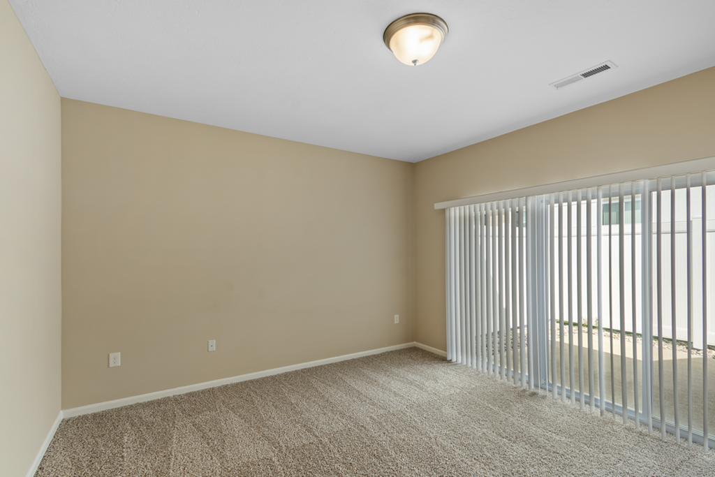 an empty living room with a large window and blinds