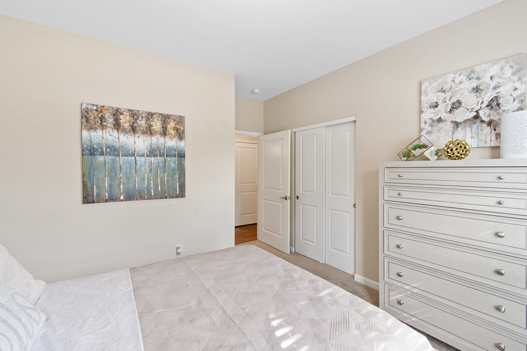 a bedroom with a bed and closets and a painting on the wall