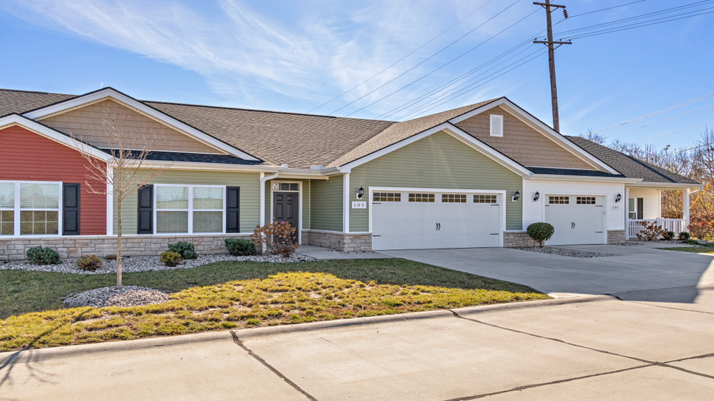 a green house with a white door and a driveway