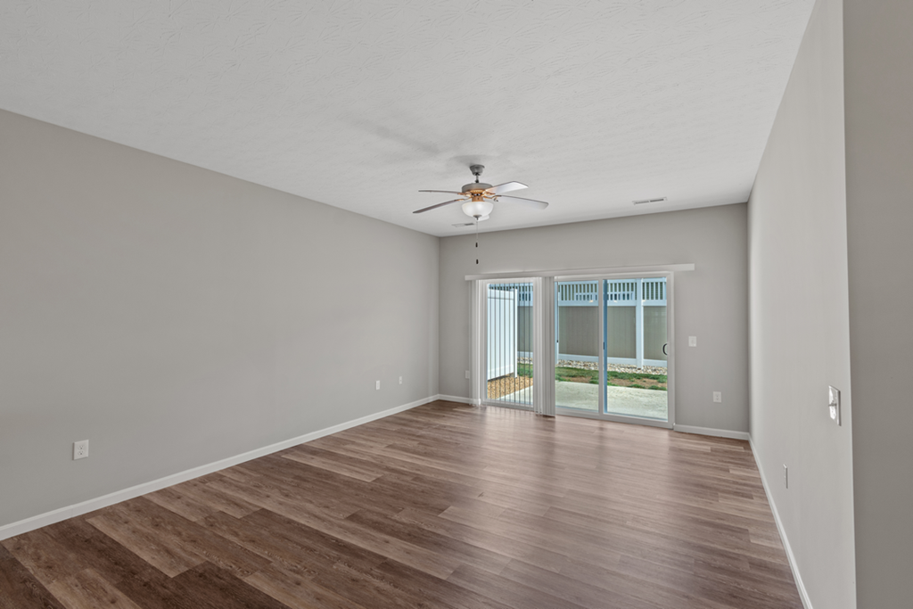 an empty living room with a ceiling fan and a window