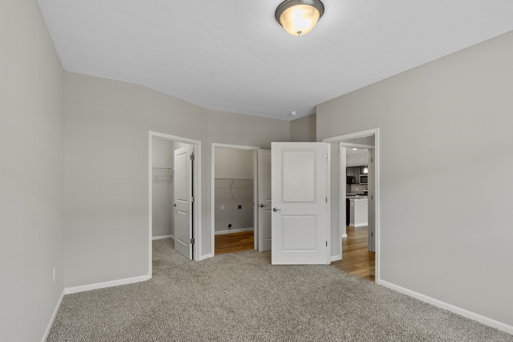 a spacious living room with white doors and a carpeted floor