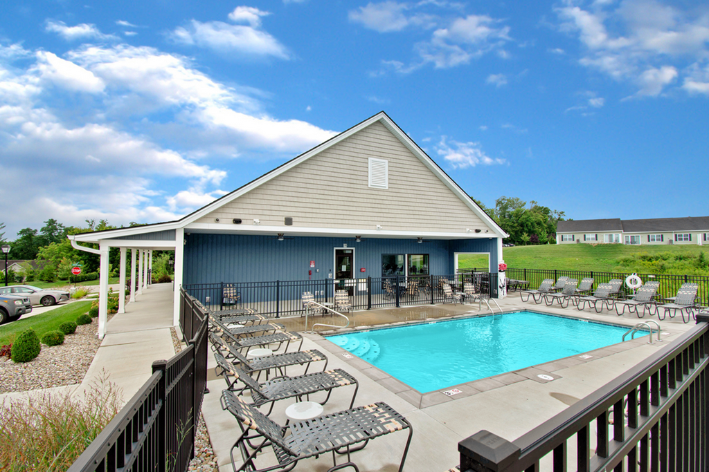 the pool and deck of a house with a pool and chairs