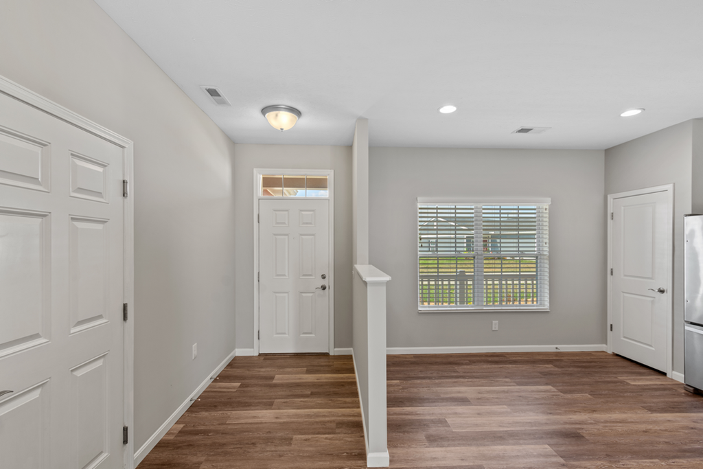 an empty hallway with white doors and a window
