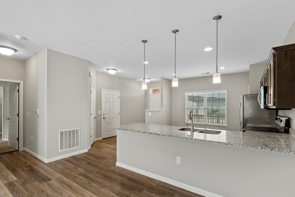 the kitchen and living room of a new home with white walls and wood flooring