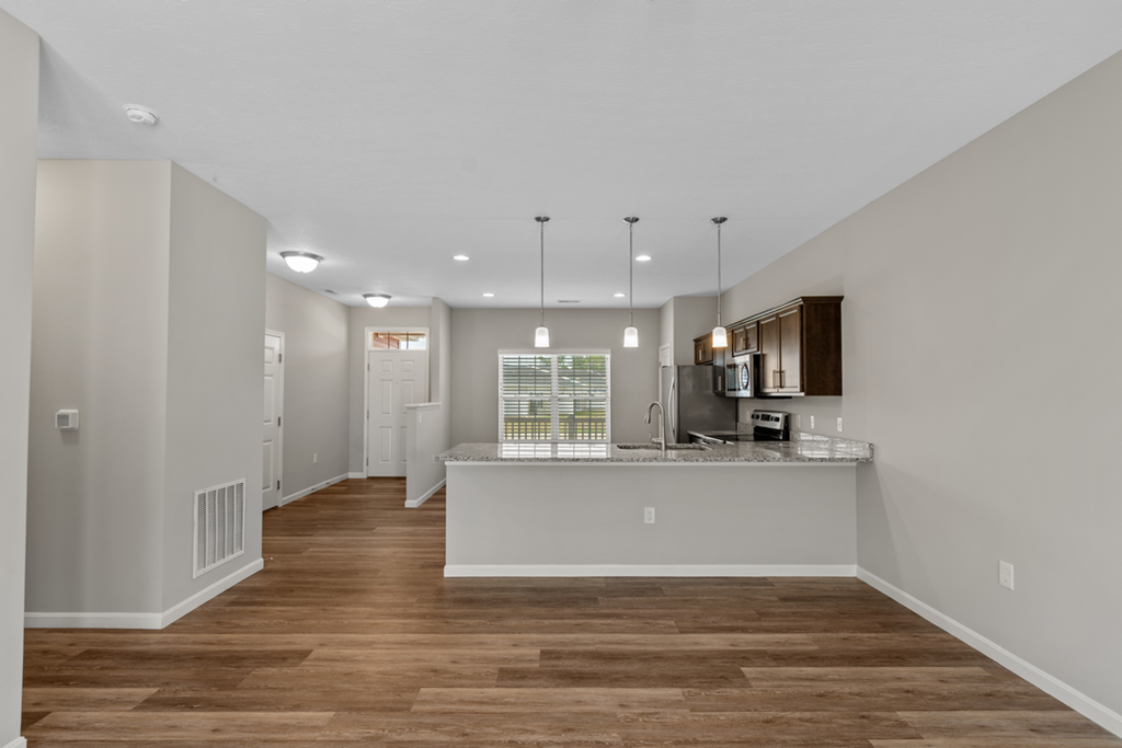 an open kitchen and living room with a wood floor and white walls