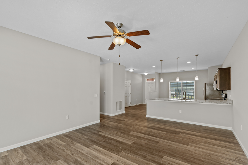 a living room with a ceiling fan and a kitchen