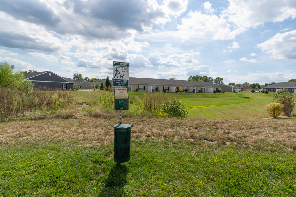 A green sign in a field with a cloudy sky in the background.