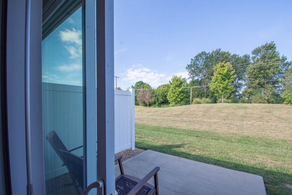A chair sits on a patio looking out to a green lawn.