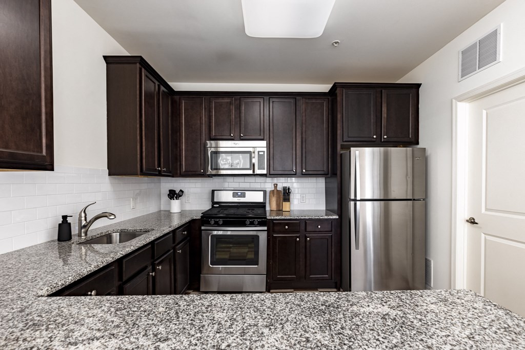 A kitchen with dark wood cabinets and granite countertops.