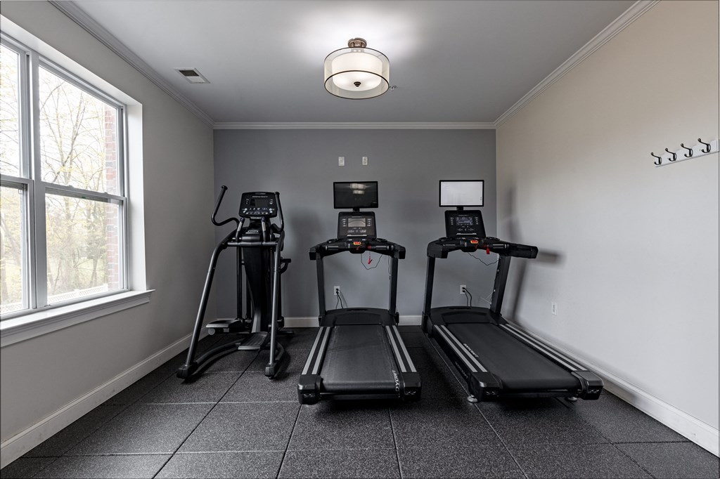 Modern fitness center at Queens Gate Apartments featuring treadmills with built-in screens and an elliptical, designed to support your active lifestyle.