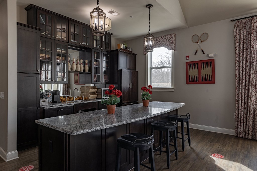 Elegant clubhouse kitchen at Queens Gate Apartments, featuring granite countertops, bar seating, and stylish cabinetry, perfect for resident events and gatherings.