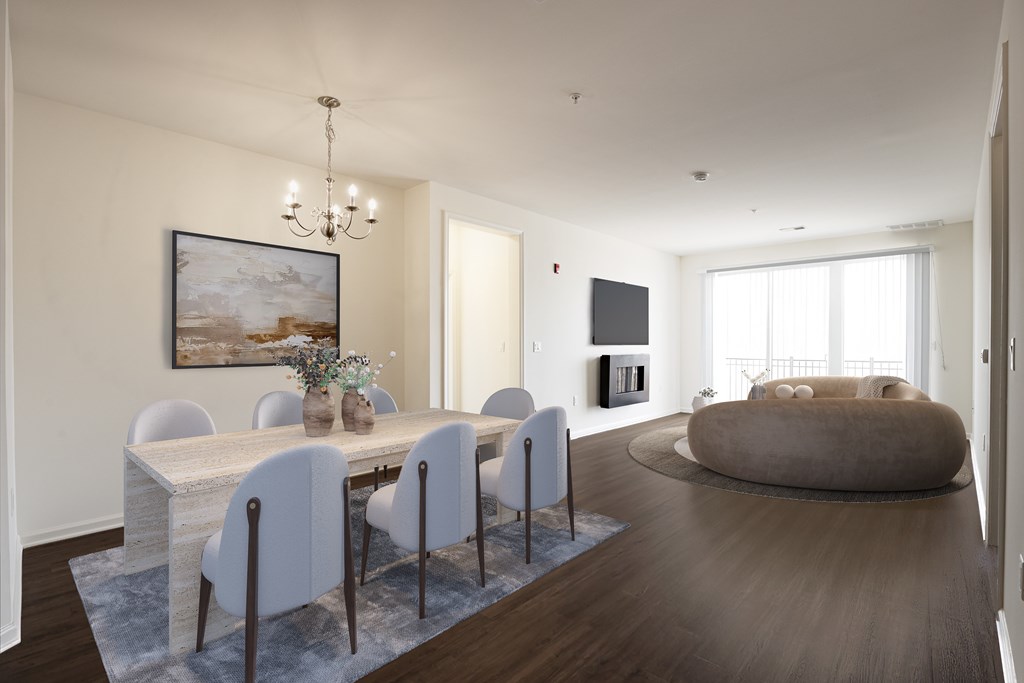 A Spacious open-concept living and dining area in a modern apartment at Queens Gate Apartments in Bound Brook, NJ. Features a fireplace, and large windows leading to a balcony, allowing plenty of natural light.