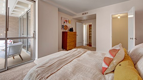 A bedroom with a bed and a chair outside the window.