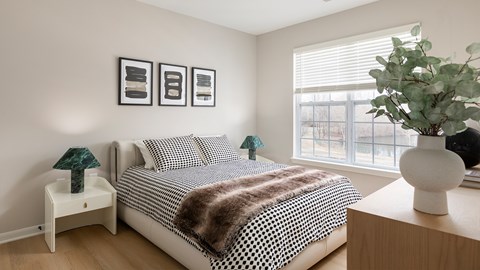 A bedroom with a bed, nightstands, and a plant.