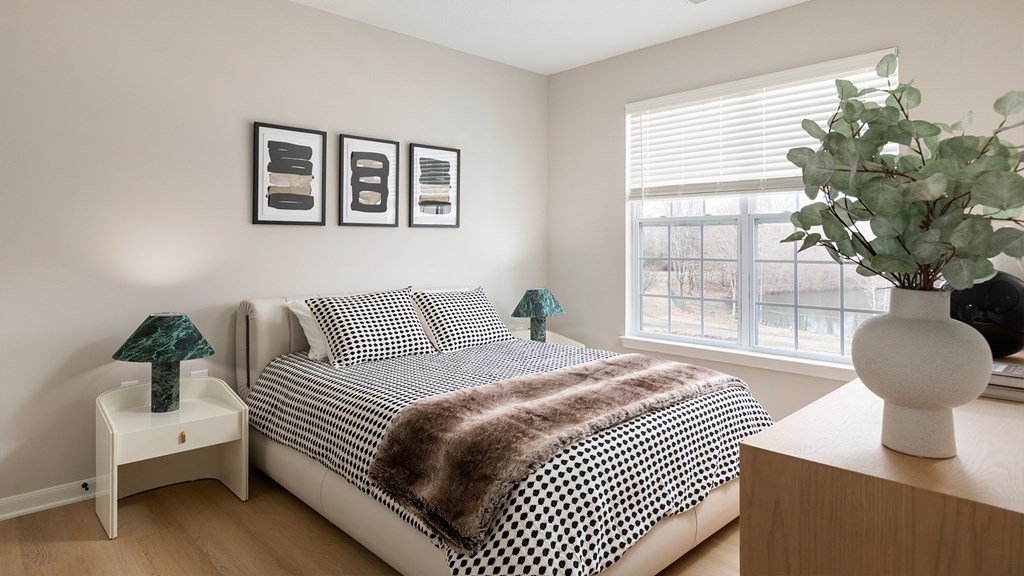 A bedroom with a bed, nightstands, and a plant.