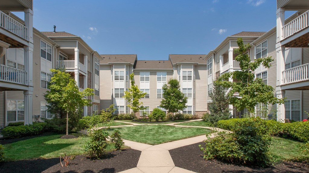 an exterior view of an apartment building with a lawn and trees