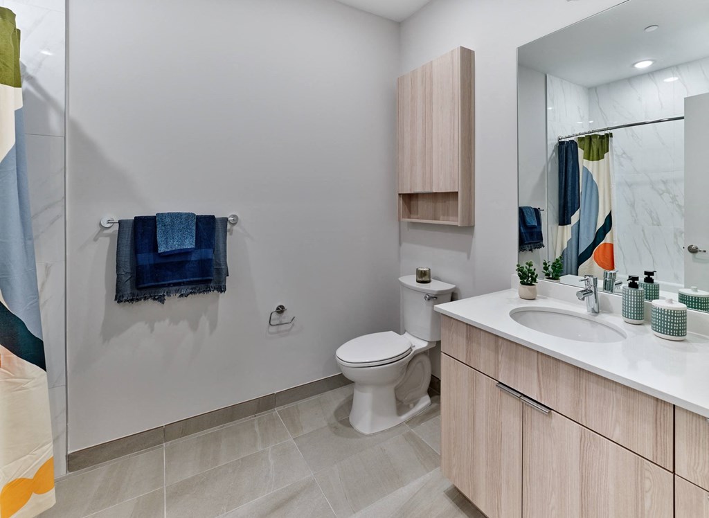 a bathroom with a toilet sink and shower and a mirror